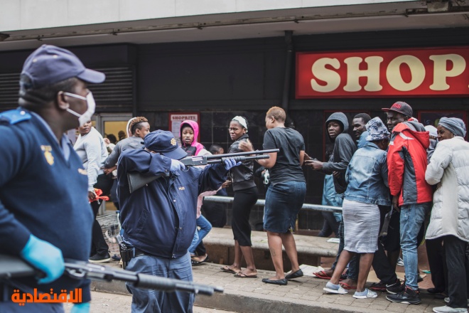 شرطي يوجه بندقيته تجاه المتسوقين لحثهم على فرض مسافة آمنة بينهم في جنوب إفريقيا