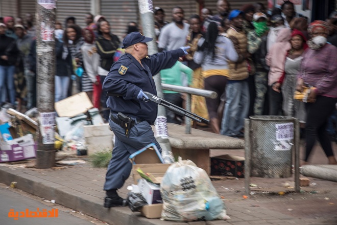 شرطي يوجه بندقيته تجاه المتسوقين لحثهم على فرض مسافة آمنة بينهم في جنوب إفريقيا
