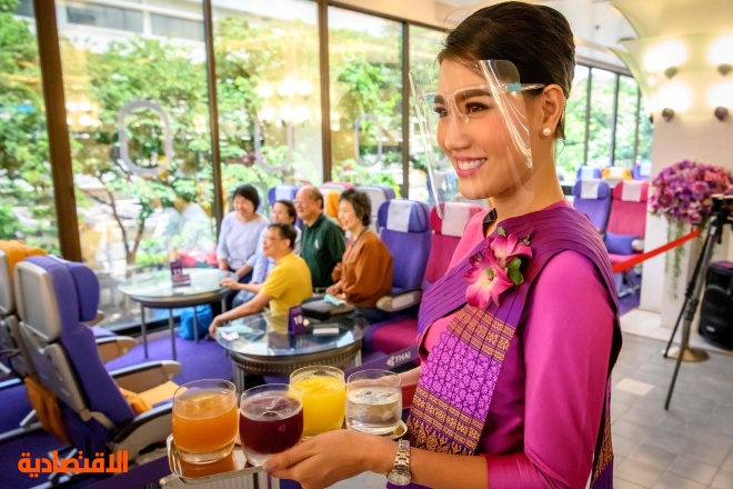  مضيفة طيران تابعة للخطوط التايلاندية تقدم الوجبات في مطعم على طراز طائرة في مقر الشركة  