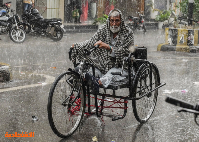 هندي يشق طريقه على دراجة وسط أمطار غزيرة شهدتها مدينة أمريتسار