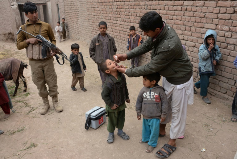 شرطي يقف حارسا بينما يتم تطعيم اطفال ضد شلل الاطفال في جلال اباد في افغانستان.