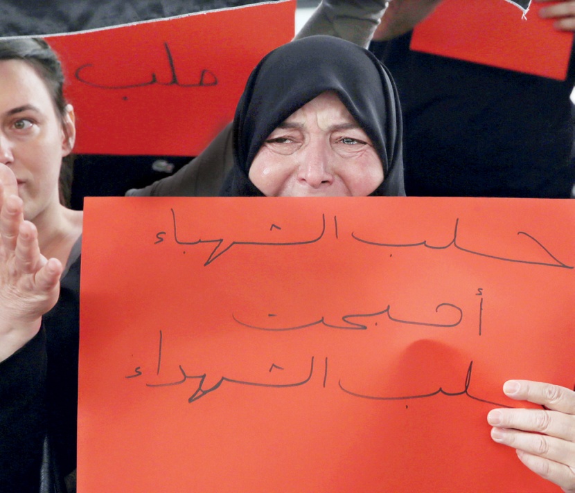 مسنة سورية في لحظة بكاء وهي تحمل لافتة كتب عليها " حلب أصبحت حلب الشهداء "