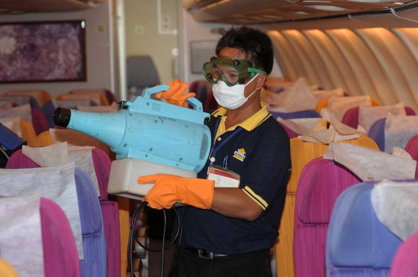 عامل تايلاندي يقوم برش المواد الكيميائية لمنع انتشار أنفلونزا الخنازير على أحد طائرات الخطوط الجوية التايلندية