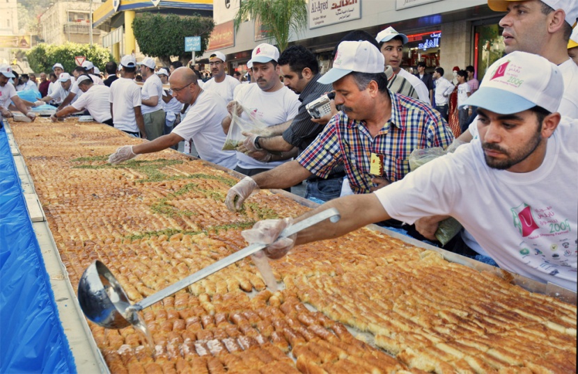 طهاه فلسطينيون يعدون أكبر "كنافة" في العالم في مدينة نابلس ويبلغ وزنها 1.765  كلغ (3٬891 رطل) بطول 74 مترا (243 قدما) وسيطالبون 