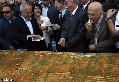 طهاه فلسطينيون يعدون أكبر "كنافة" في العالم في مدينة نابلس ويبلغ وزنها 1.765  كلغ (3٬891 رطل) بطول 74 مترا (243 قدما) وسيطالبون 