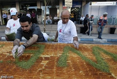 طهاه فلسطينيون يعدون أكبر "كنافة" في العالم في مدينة نابلس ويبلغ وزنها 1.765  كلغ (3٬891 رطل) بطول 74 مترا (243 قدما) وسيطالبون 