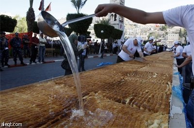 طهاه فلسطينيون يعدون أكبر "كنافة" في العالم في مدينة نابلس ويبلغ وزنها 1.765  كلغ (3٬891 رطل) بطول 74 مترا (243 قدما) وسيطالبون 