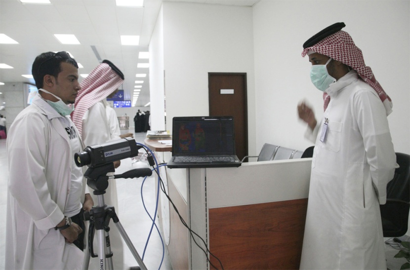 أطباء و مسؤولون من وزارة الصحة يراقبون درجة حرارة المسافرين الواصلين إلى مطار الملك عبد العزيز الدولي في جدة.