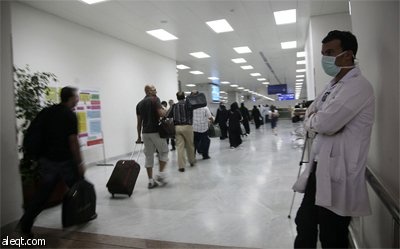 أطباء و مسؤولون من وزارة الصحة يراقبون درجة حرارة المسافرين الواصلين إلى مطار الملك عبد العزيز الدولي في جدة.