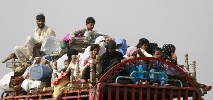 نازحو وادي سوات يجلسون فوق شاحنة مع أمتعتهم أثناء عودتهم إلى قراهم.