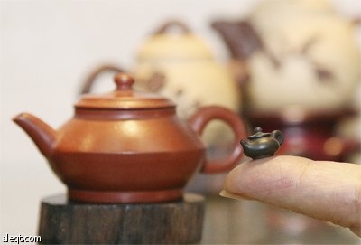 تايوانية تحمل إبريق شاي (من الطين) حجمه يماثل حجم نواه الفول السوداني في مدينة تايتشونج يستخدم للزينة والحملات الدعائية.