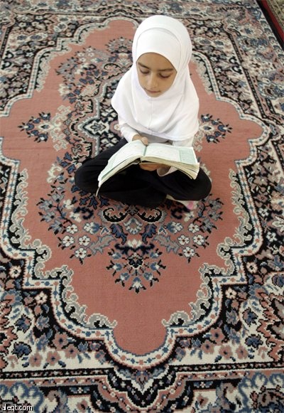 فتاة فلسطينية تقرأ القرآن الكريم في مسجد في مدينة نابلس في اليوم الأول من أيام شهر رمضان المبارك.