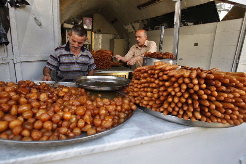 فلسطينيون  يبيعون الحلويات في متجر في مدينة نابلس خلال اليوم الثاني من شهر رمضان.