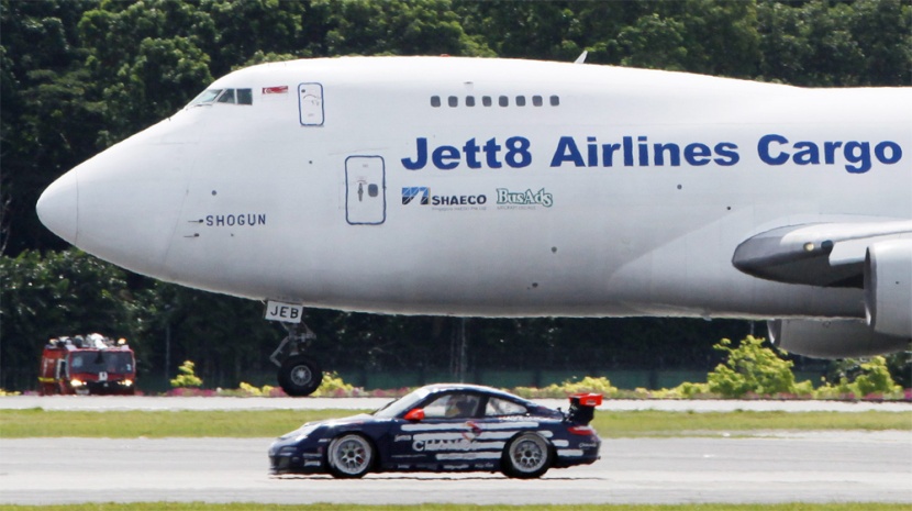 بورش 911 كاريرا GT3 تسابق طائرة من طراز بوينج 747 على مدرج مطار شانغي في سنغافورة.