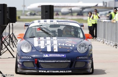 بورش 911 كاريرا GT3 تسابق طائرة من طراز بوينج 747 على مدرج مطار شانغي في سنغافورة.