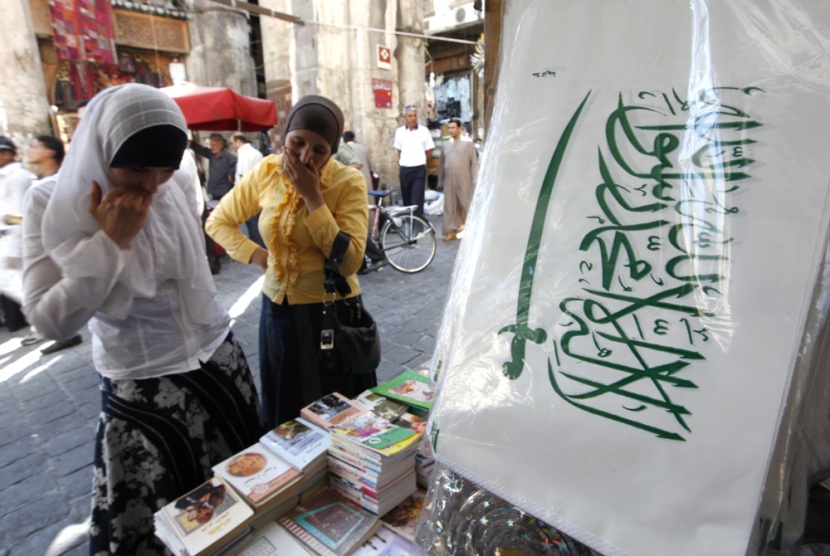 سوريتان تتبضعان من متجر متخصص في بيع الكتب وأدوات الزينة إلى جانب الأعلام السعودية في سوق الحميدية الشعبي في دمشق.