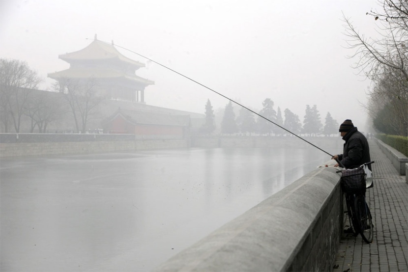 صياد صيني يصطاد السمك في الصباح الباكر تحت الضباب الكثيف الذي تشهده الصين.