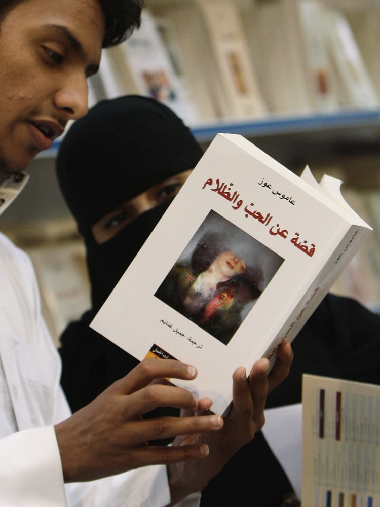سعوديون يلقون نظرة على النسخة العربية من كتاب الإسرائيلي عاموس عوز "قصة عن الحب والظلام" والمعروض في معرض الرياض الدولي الخامس ل
