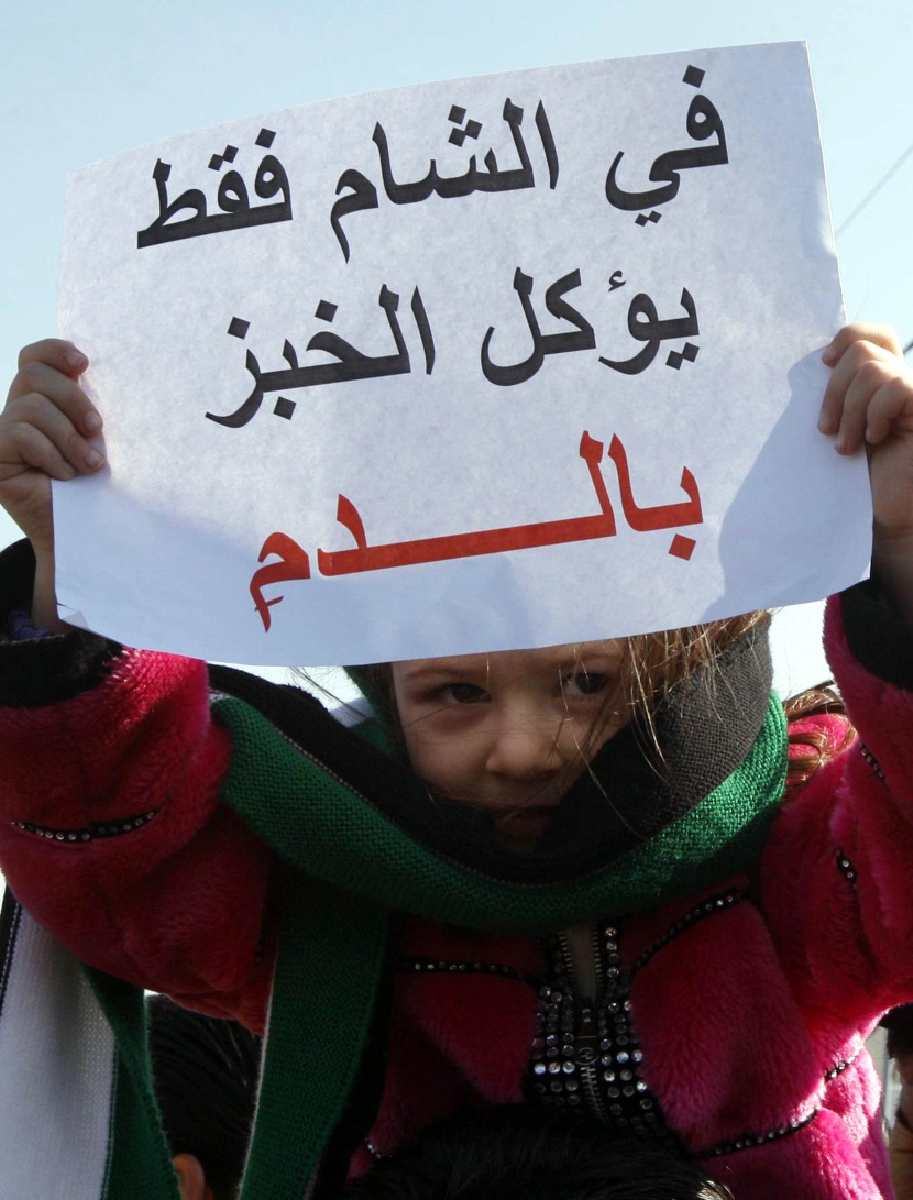 طفل يحمل لافتة كتب عليها في الشام فقط يؤكل الخبز بالدم خلال مظاهرة مع السوريين الذين يعيشون في الأردن