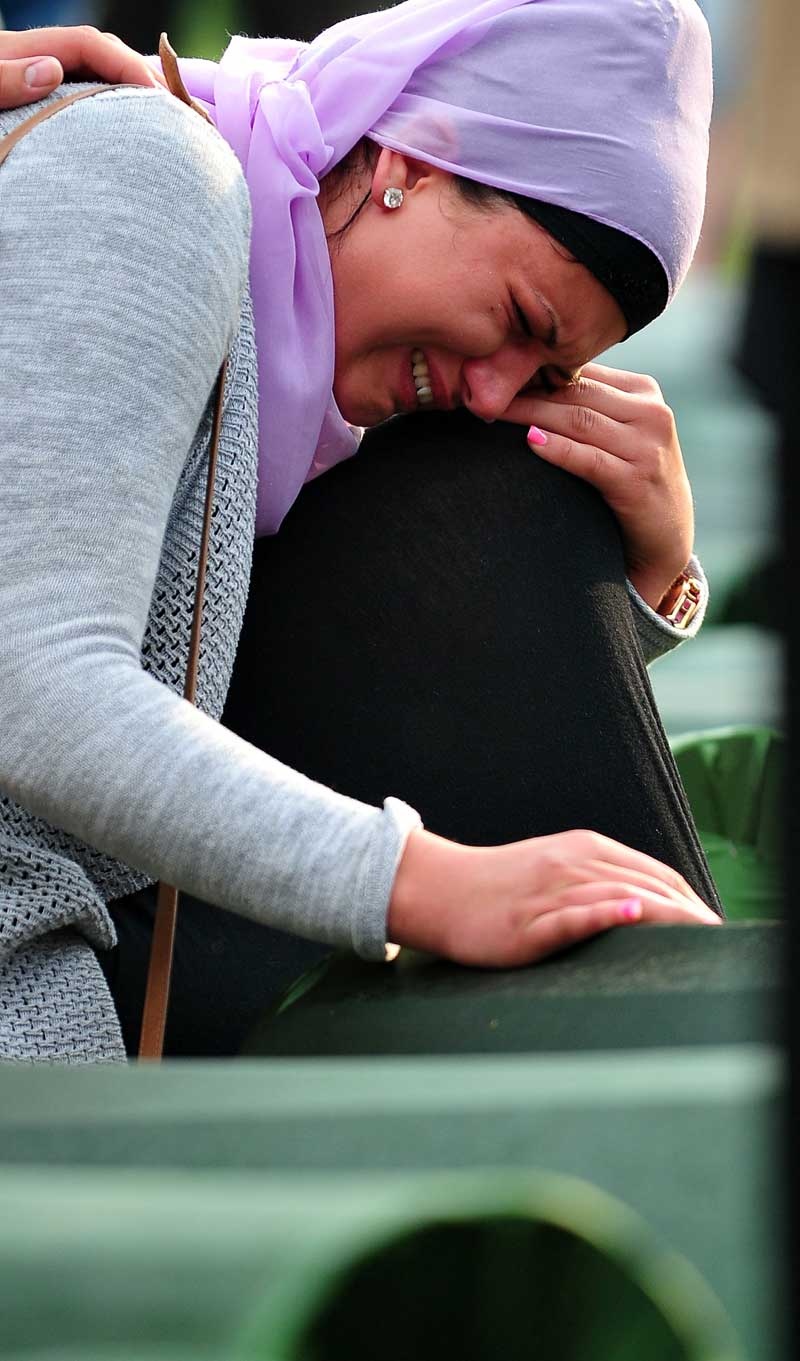 إمراة مسلمة تبكي بجوار قبر لقريبها في الذكرى الـ18 لمجزرة سربيرينيتشا في البوسنة