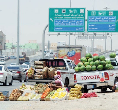 باعة خضار يعرضون بضائعهم على طريق أبو بكر الصديق تحت أشعة الشمس في درجة حرارة تزيد على 40 ْ