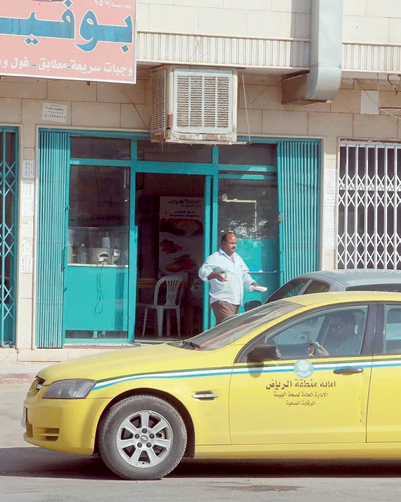 عامل «بوفيه» يقدم طلباً لأحد الزبائن في الخارج رغم منع وزارة البلدية. ويأتي ذلك خلال وجود سيارة تابعة لـ «الأمانة» في الموقع