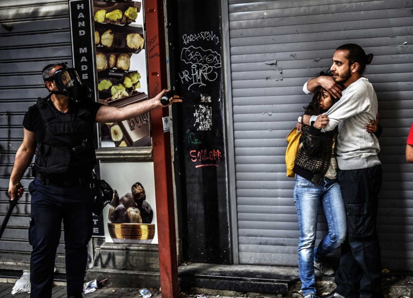 متظاهر يحمي امرأة من قوات الشرطة في ساحة تقسيم في تركيا .