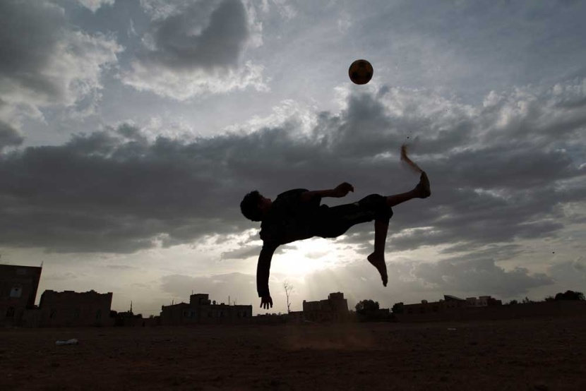صبي يركل الكرة في الهواء أثناء مباراة لكرة القدم في العاصمة اليمنية صنعاء