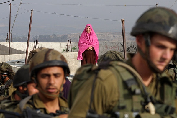 امرأة فلسطينية تقف بعيدا عن الجيش الإسرائيلي