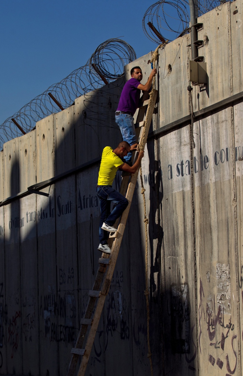 قصة مصورة: فلسطينيون يستخدمون السلالم لتسلق الجدار الفاصل في طريقهم إلى المسجد الأقصى