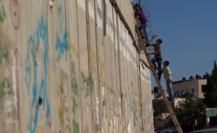 قصة مصورة: فلسطينيون يستخدمون السلالم لتسلق الجدار الفاصل في طريقهم إلى المسجد الأقصى