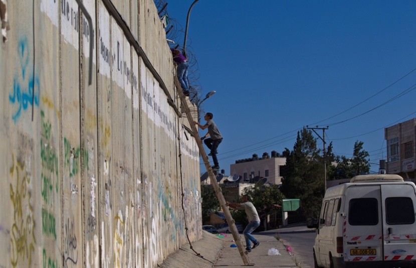 قصة مصورة: فلسطينيون يستخدمون السلالم لتسلق الجدار الفاصل في طريقهم إلى المسجد الأقصى