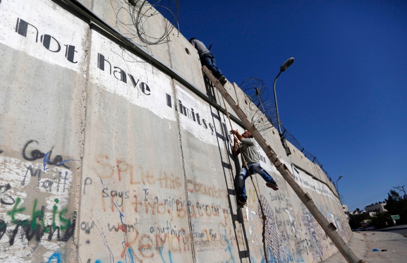 قصة مصورة: فلسطينيون يستخدمون السلالم لتسلق الجدار الفاصل في طريقهم إلى المسجد الأقصى