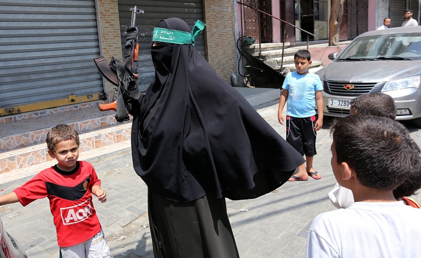 قصة مصورة: امرأة فلسطينية تحمل سلاحاً احتجاجاً على مقتل الفتى أبوخضير