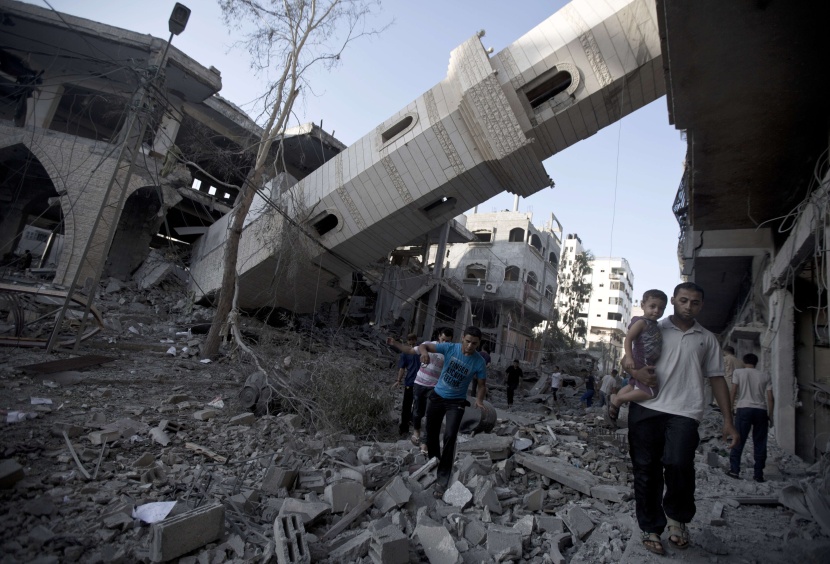 فلسطينيون يمشون بالقرب من مسجد دمر من قبل الجيش الإسرائيلي في غزة