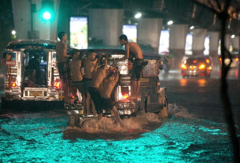 فتيان  يستقلون حافلة لعبور شارع غمرته مياه السيول في مانيلا