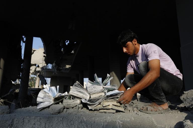 فلسطيني يتفقد نسخا من القرآن الكريم تضررت جراء قصف مسجد في غزة