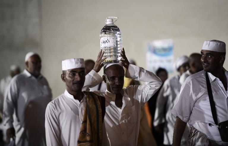 حاج في مكة يحمل قارورة من مياه زمزم بعد اداء صلاة العشاء