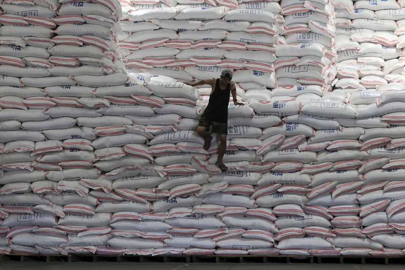 عامل يأخذ استراحة فوق أكياس من الأرز داخل مستودع للهيئة الوطنية للأغذية في الفلبين