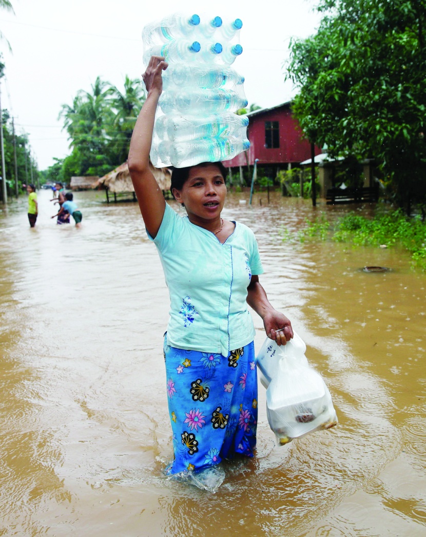 امرأة تحمل زجاجات المياه والأغذية التي وزعتها منظمة إغاثة على سكان في ميانمار
