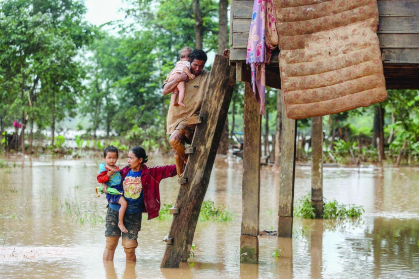 زوجان يحملان طفليهما إلى منزلهما في منطقة غمرتها الفيضانات نتيجة انهيار سد في مقاطعة أتابيو