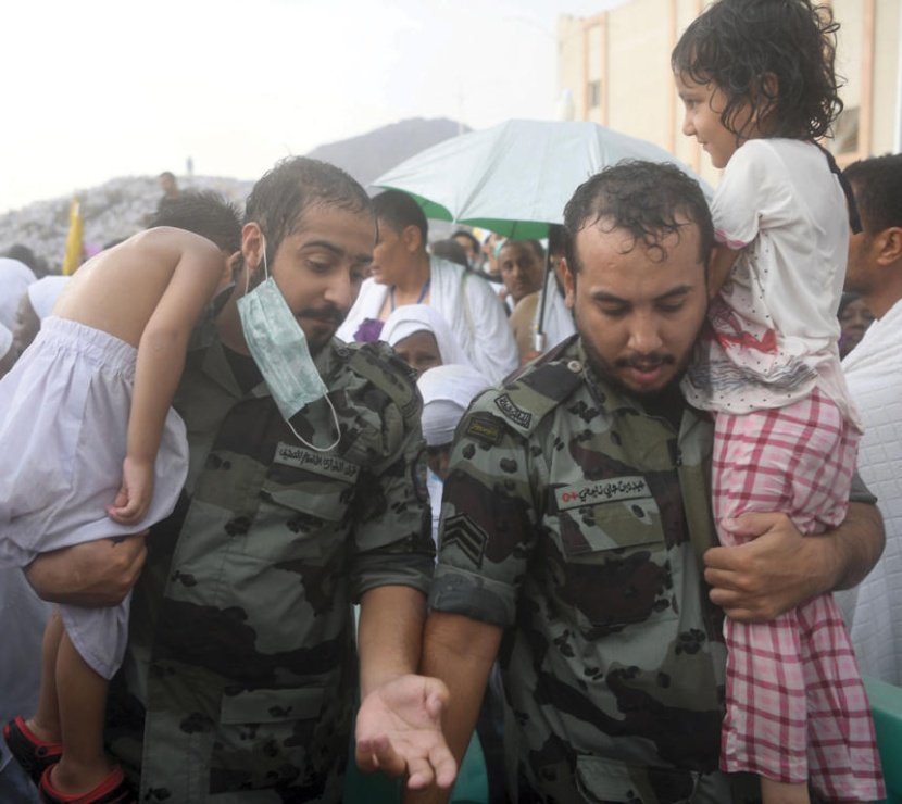 رجلا أمن في عمل إنساني يحملان طفلين من أبناء الحجاج في عرفات أمس