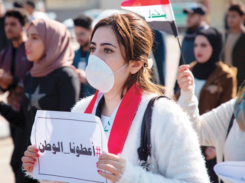عراقية تحمل لافتة كتب عليها "أعطونا الوطن" خلال تظاهرات بالقرب من مقر الحكومة في البصرة