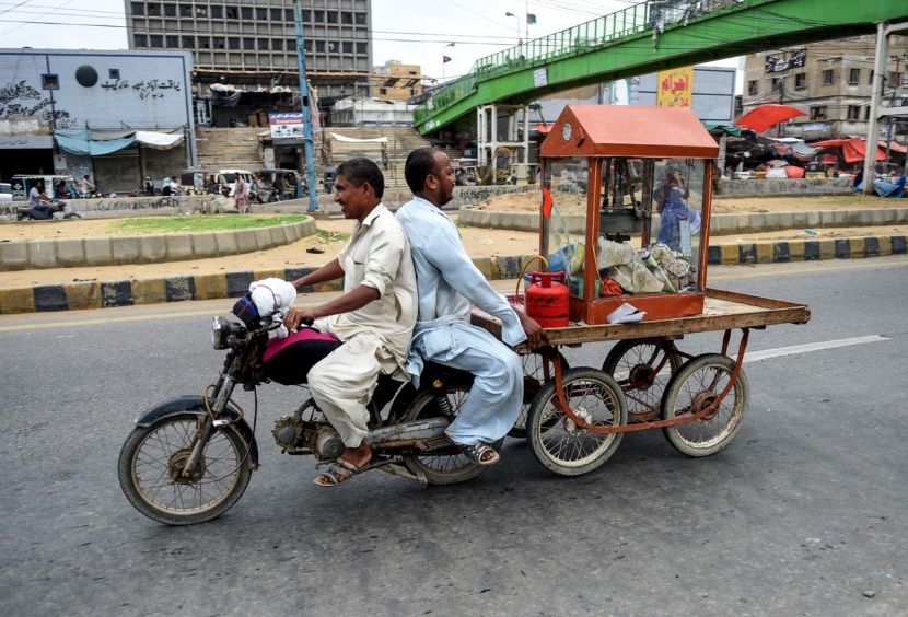 بائع فشار يسحب عربته عبر دراجة نارية في أحد شوارع مدينة كراتشي الباكستانية