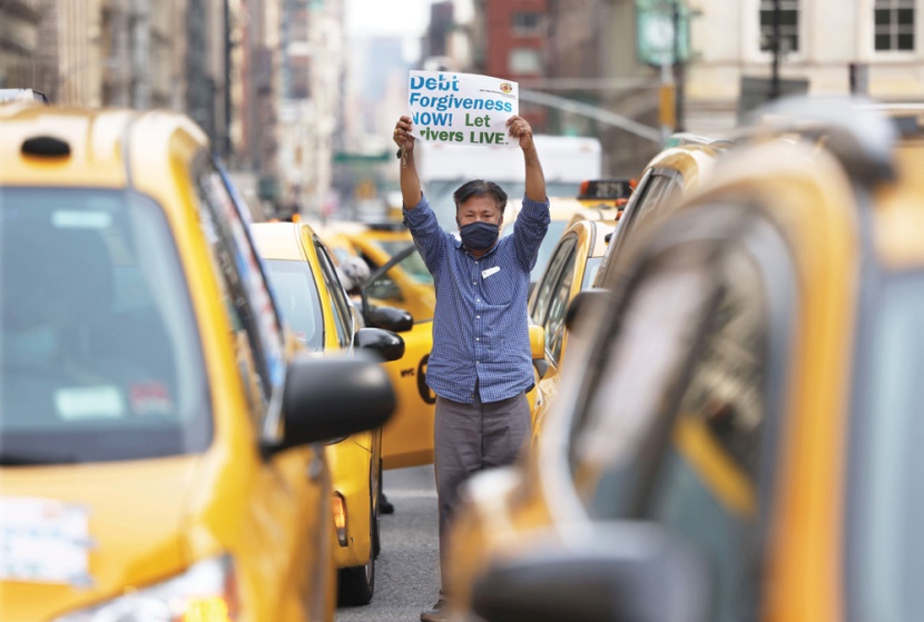 سائق أجرة يحمل لافتة خلال مؤتمر صحافي يعقده زملاؤه أمام مجلس مدينة نيويورك يطالبون فيه بإعفائهم من الديون