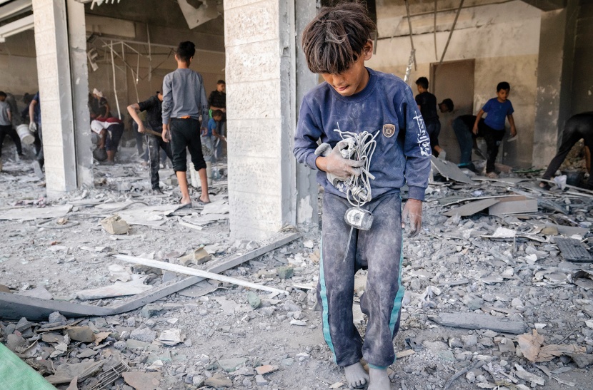 أطفال فلسطينيون يزيلون حطام مبنى تضرر بشدة أمس جراء غارة إسرائيلية قبل وقف إطلاق النار
