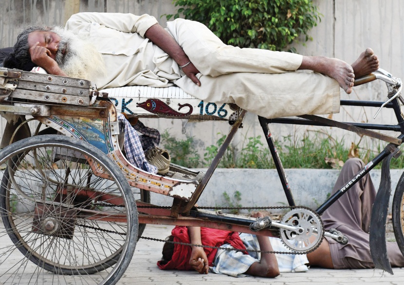 رجل ينام على دراجته وآخر على الأرض في طريق عام في مدينة أمريتسار الهندية 