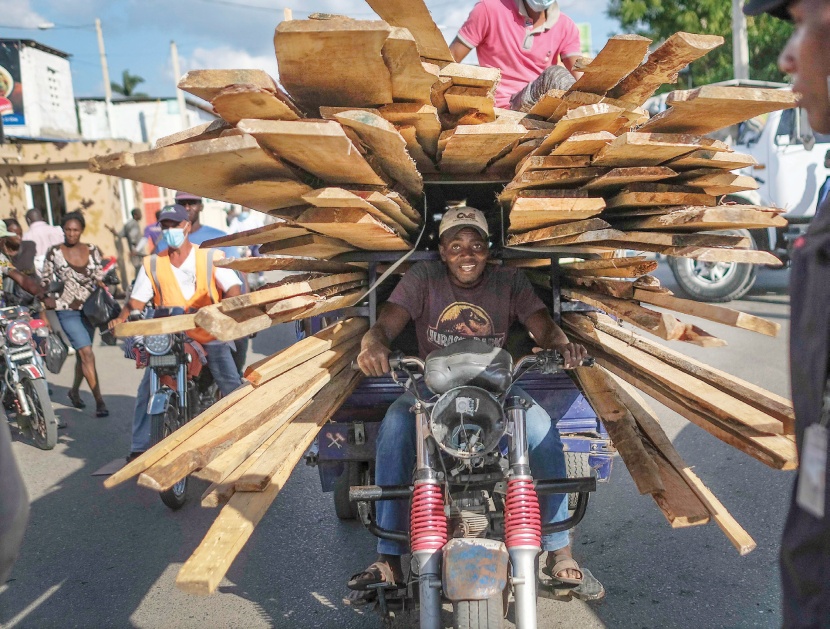 رجل يحمل قطعا من الخشب على دراجة بعد شرائها من سوق في بلدة داجابون الحدودية